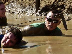 Contestants slither through mud to get beneath barbed wire. Photo by Alhele Curry.